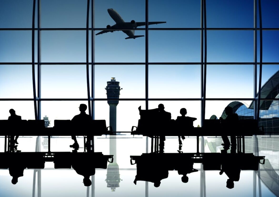 Futuristic airline terminal in silhouette, showing a plane taking off with travelers in the foreground and air traffic control in the background.
