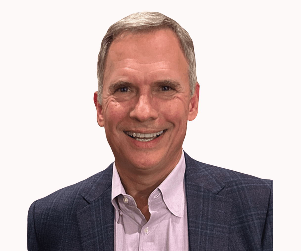 A smiling man with short hair, wearing a blazer over a light shirt, standing against a plain background.