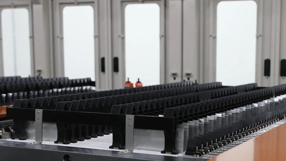 A workshop interior featuring rows of black holders on a metallic base, likely for organizing tools or components, with a blurred background.