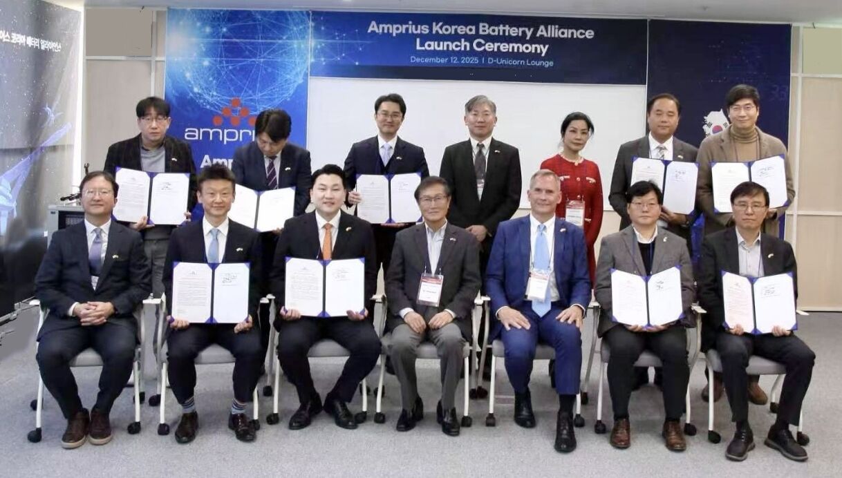 A formal event with a group of professionals seated, holding certificates, celebrating the launch of the Amprius Korea Battery Alliance on December 12, 2025.