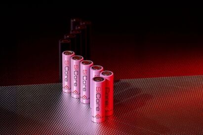 A series of pink and black cylindrical batteries arranged in a linear formation, set against a textured metallic background with subtle lighting.